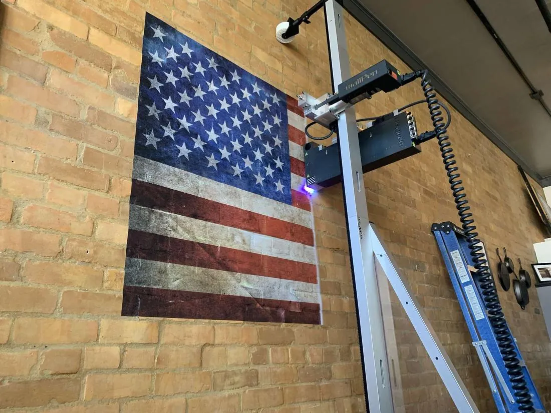 wallPen wall printer printing an American flag mural on a brick restaurant wall, UV light glowing